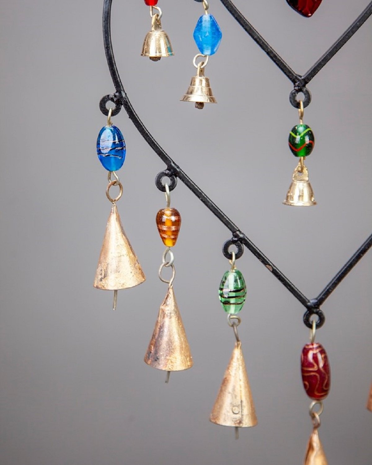 A colorful double heart design hanging chime made of glass beads and brass bells, showcasing vibrant colors and intricate craftsmanship.