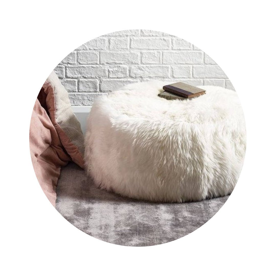 Elegant round pouf made from 100% natural ivory sheepskin with a non-slip leather base, perfect for seating or footrest.