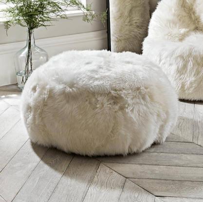 Elegant round pouf made from 100% natural ivory sheepskin with a non-slip leather base, perfect for seating or footrest.