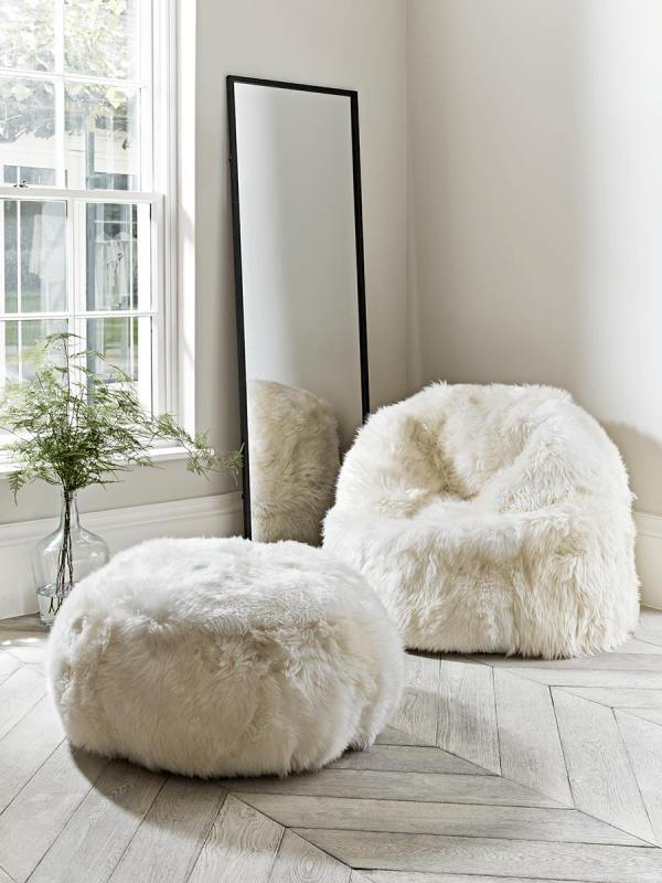 Elegant round pouf made from 100% natural ivory sheepskin with a non-slip leather base, perfect for seating or footrest.