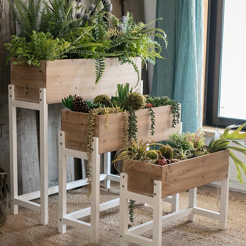 Elevated Wood Planter Box in light brown with a white stand, showcasing three sizes for versatile gardening.