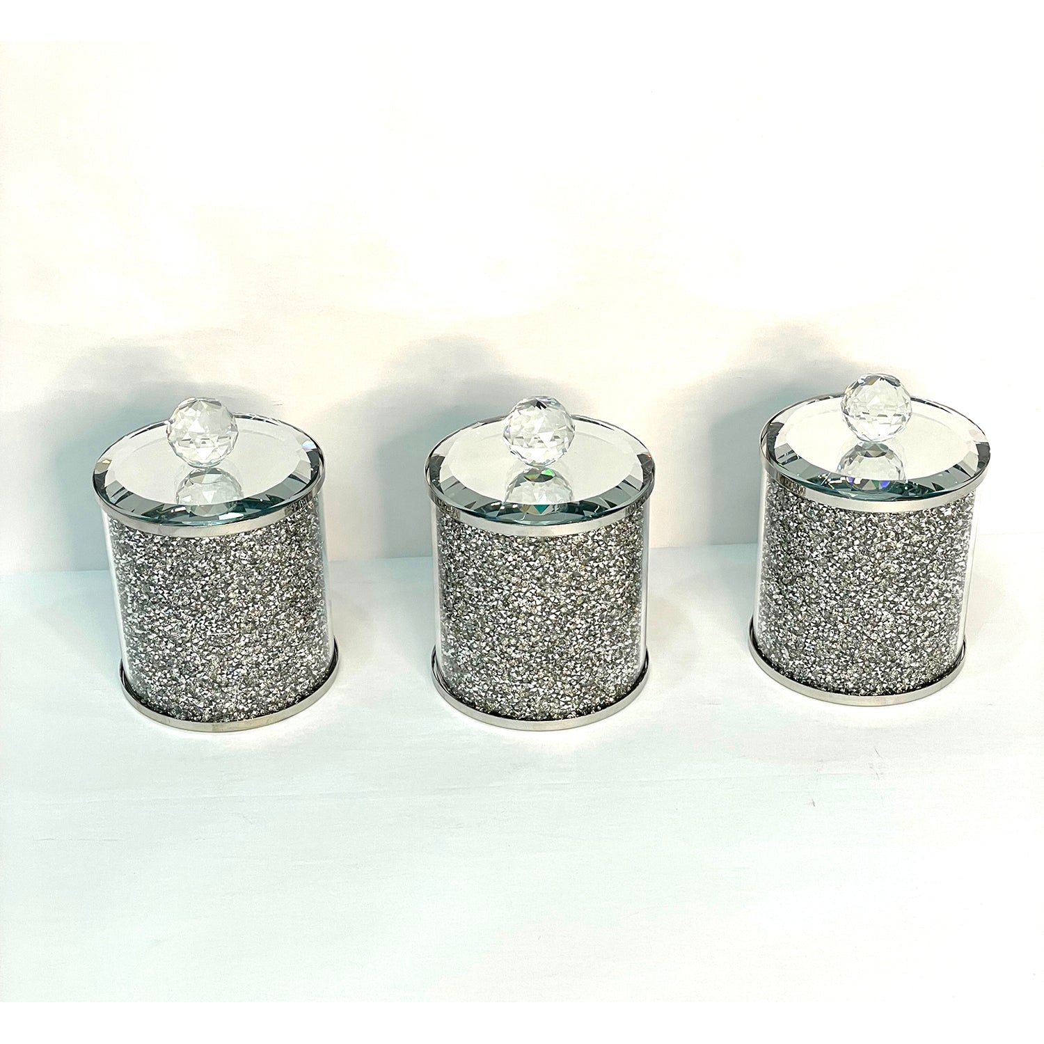 Exquisite three glass canister set with silver crushed diamond finish, featuring decorative chrome base and glass lids with handles.