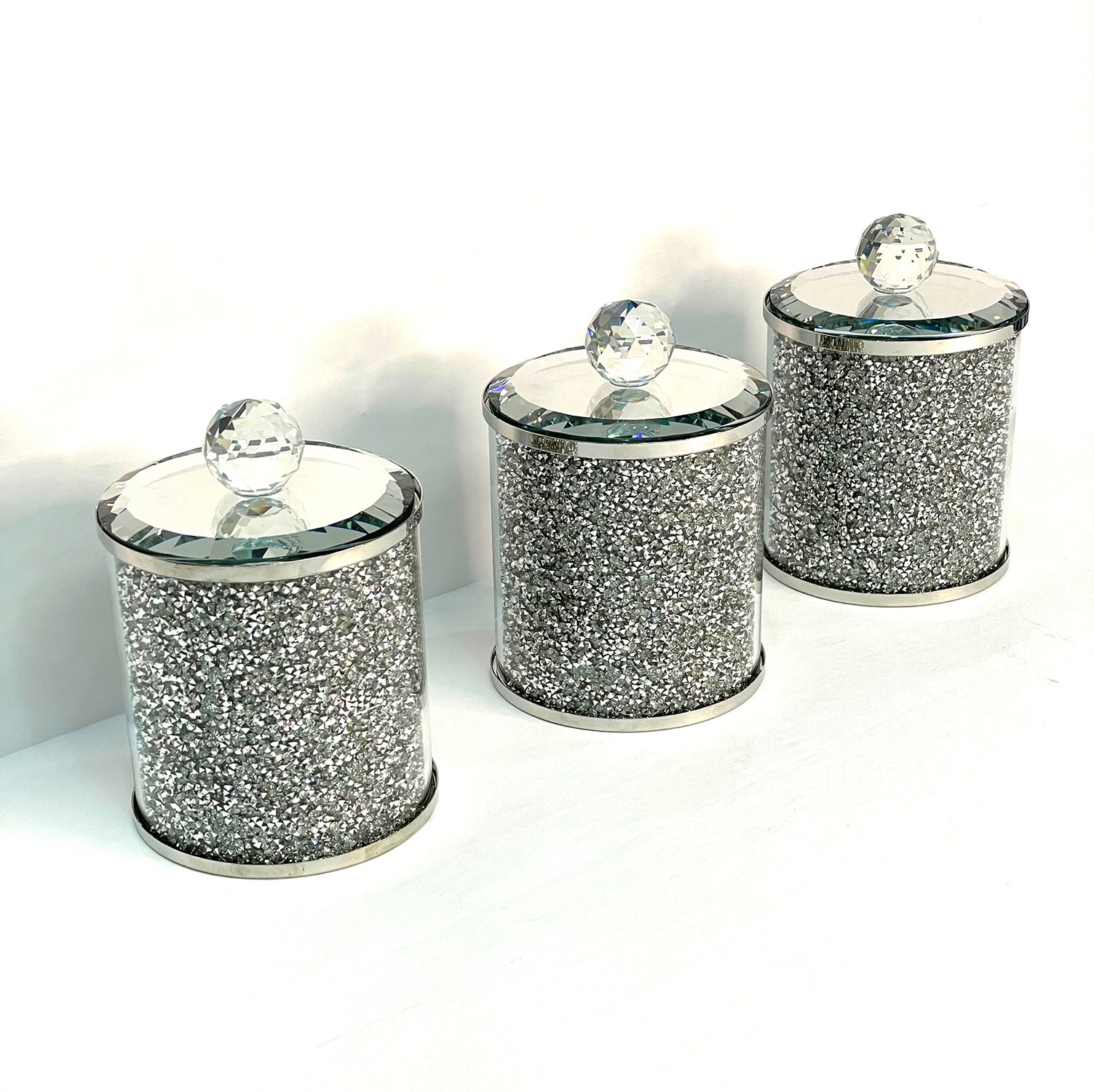 Exquisite three glass canister set with silver crushed diamond finish, featuring decorative chrome base and glass lids with handles.