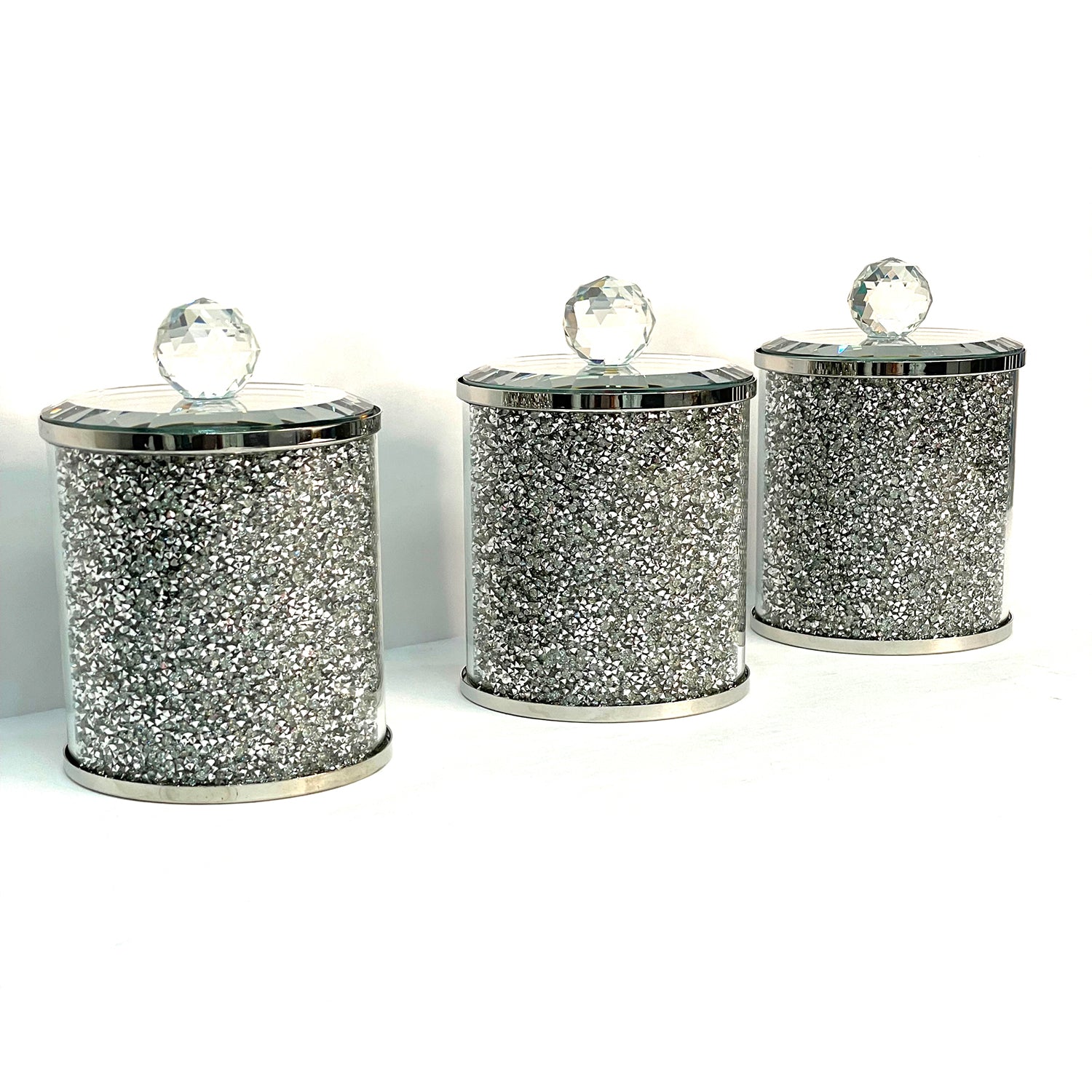 Exquisite three glass canister set with silver crushed diamond finish, featuring decorative chrome base and glass lids with handles.