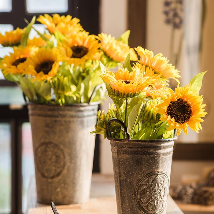 A vibrant 28-inch tall faux silk sunflower stem with a large bloom and a bud, showcasing bright yellow petals and green leaves.