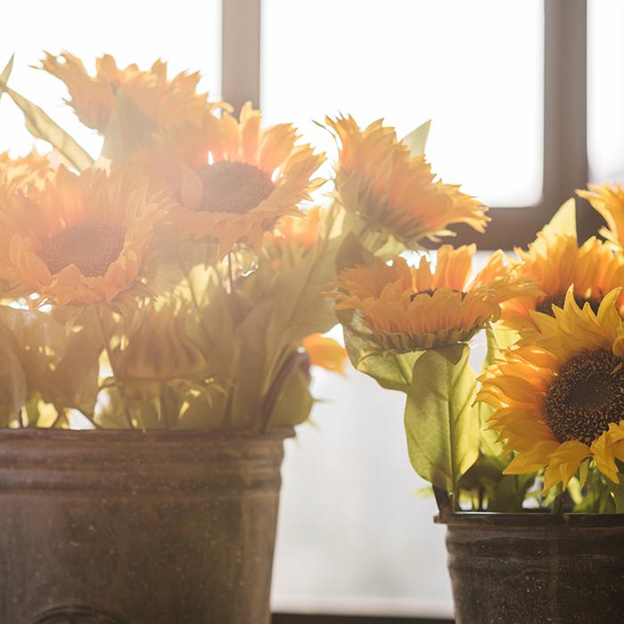 A vibrant 28-inch tall faux silk sunflower stem with a large bloom and a bud, showcasing bright yellow petals and green leaves.