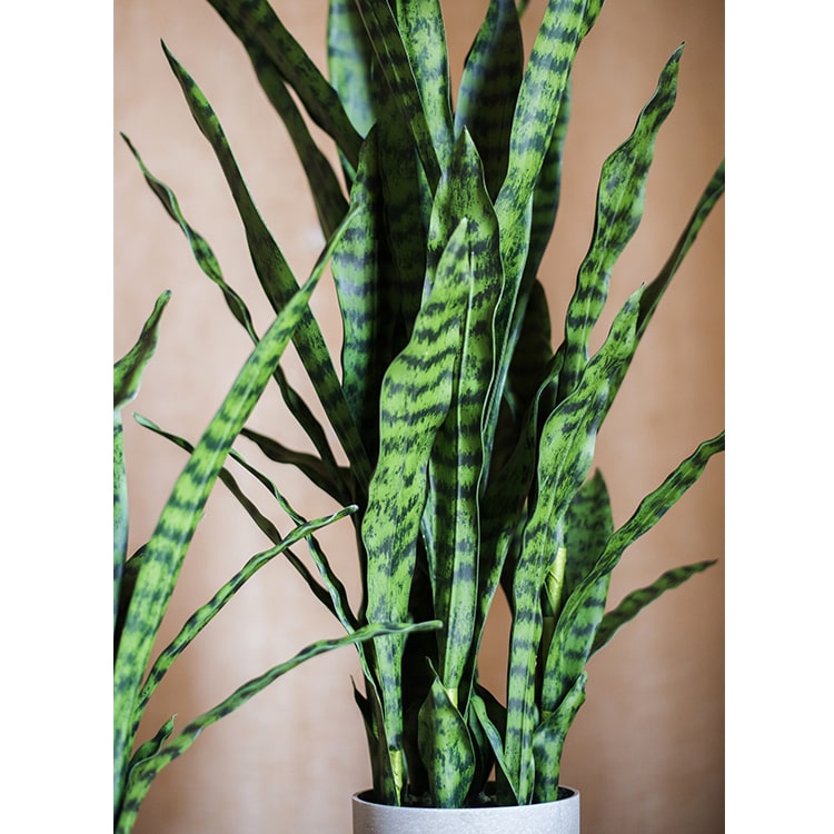 A realistic faux artificial snake plant in a decorative pot, showcasing vibrant green leaves and a modern design.