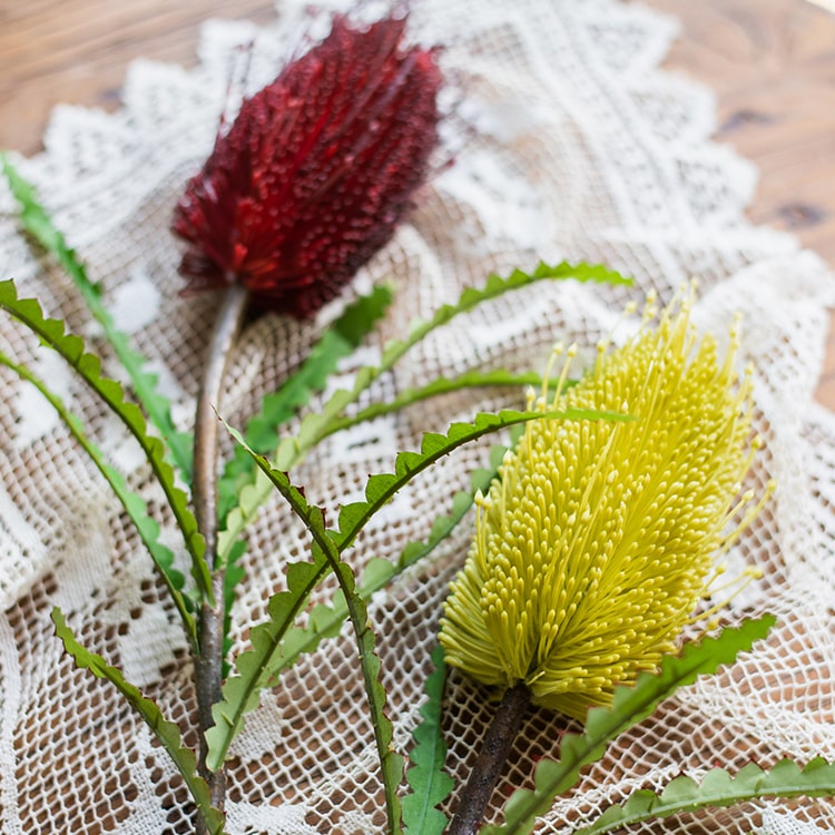 28-inch tall Faux Banksia Integrifolia silk flower with vibrant red and yellow blooms and green leaves, perfect for floral arrangements.