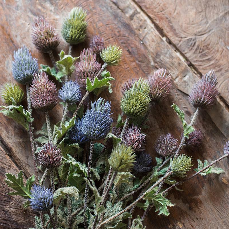 A 26-inch tall faux silk artificial thistle flower stem with three blooms in blue, green, and red, showcasing realistic petals and elegant design.