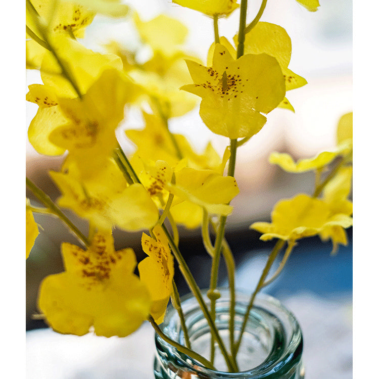 A vibrant yellow faux silk artificial Dancing Lady Orchid stem, 19 inches tall, showcasing realistic petals and leaves.