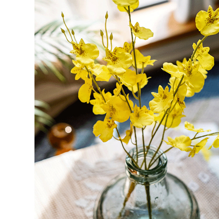 A vibrant yellow faux silk artificial Dancing Lady Orchid stem, 19 inches tall, showcasing realistic petals and leaves.