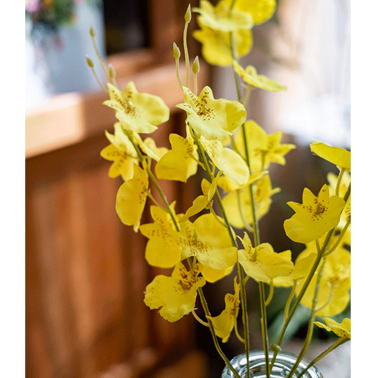 A vibrant yellow faux silk artificial Dancing Lady Orchid stem, 19 inches tall, showcasing realistic petals and leaves.