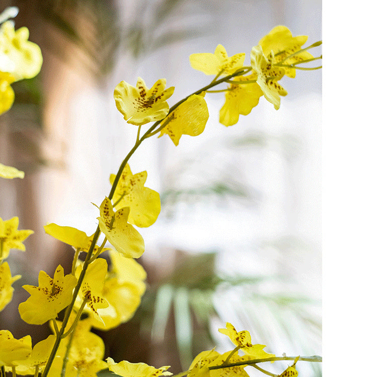 A vibrant yellow faux silk artificial Dancing Lady Orchid stem, 19 inches tall, showcasing realistic petals and leaves.