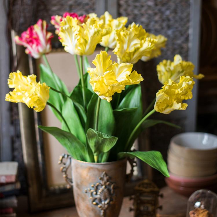 A vibrant yellow faux silk Flame Tulip flower stem, 24 inches tall, featuring lush green leaves and a realistic bloom.