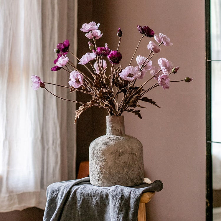 A 23-inch tall faux silk rustic poppy flower stem in purple with three blooms and one bud, featuring green leaves.