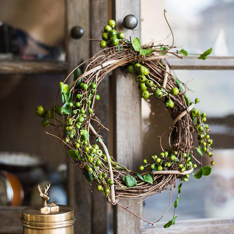 A beautifully crafted faux berry wreath made from natural rattan willow, featuring vibrant red and green artificial berries, perfect for home decor.