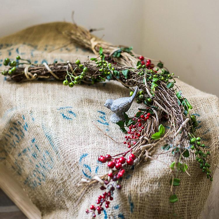 A beautifully crafted faux berry wreath made from natural rattan willow, featuring vibrant red and green artificial berries, perfect for home decor.