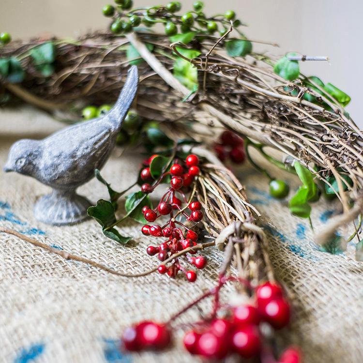 A beautifully crafted faux berry wreath made from natural rattan willow, featuring vibrant red and green artificial berries, perfect for home decor.