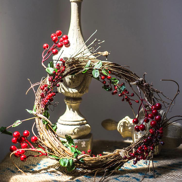 A beautifully crafted faux berry wreath made from natural rattan willow, featuring vibrant red and green artificial berries, perfect for home decor.