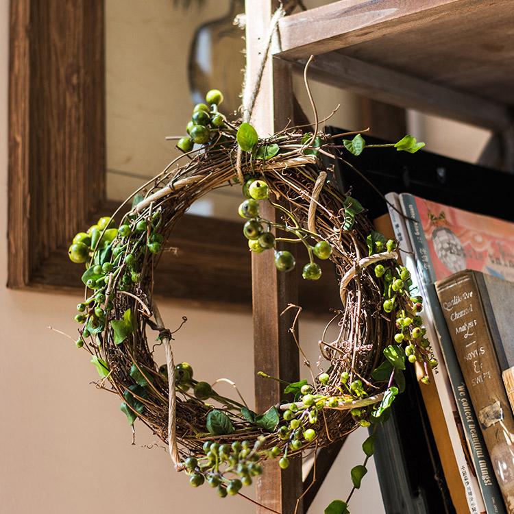 A beautifully crafted faux berry wreath made from natural rattan willow, featuring vibrant red and green artificial berries, perfect for home decor.