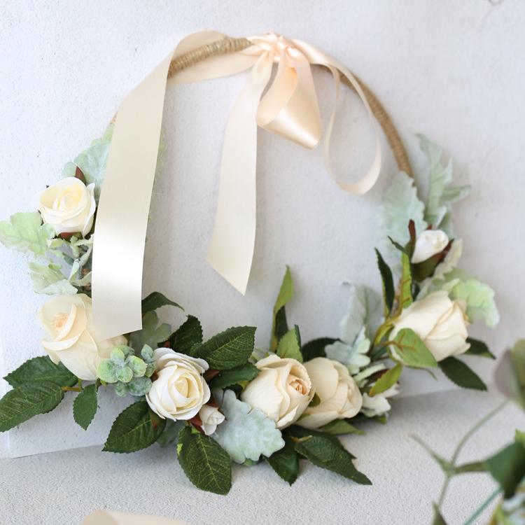 A beautiful 9-inch floral hoop featuring artificial white roses and lush green leaves, perfect for weddings and home decor.