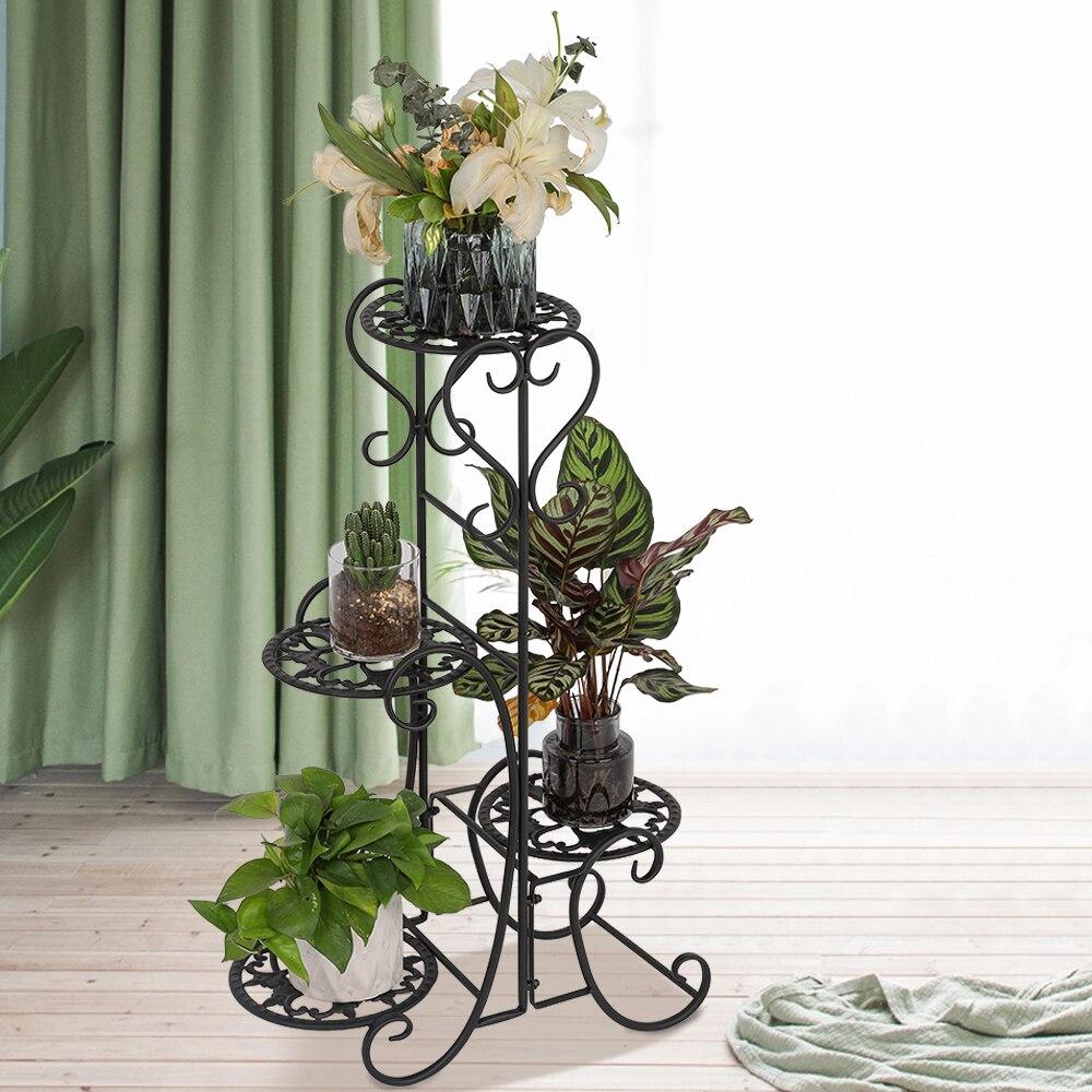 A stylish black metal garden flower stand with four rounded shelves, displaying various potted plants in an outdoor setting.