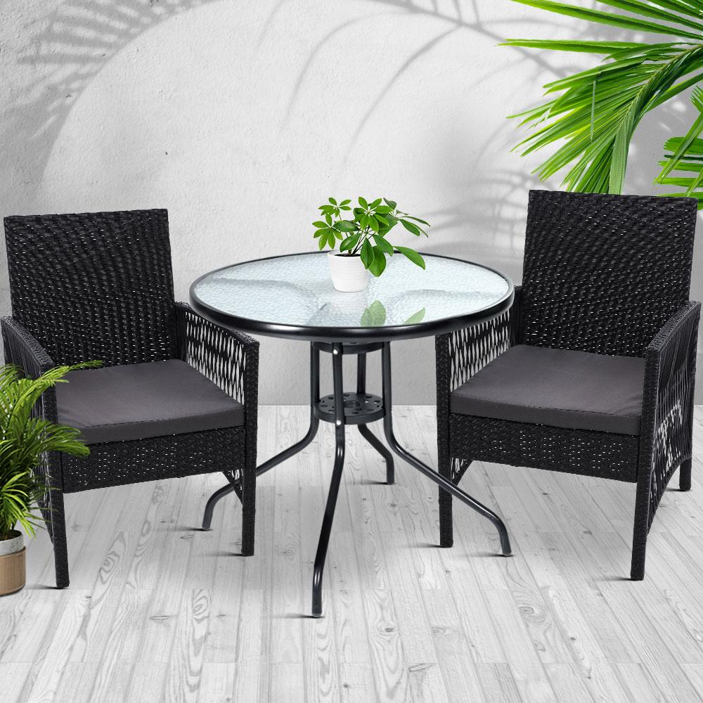 Gardeon Outdoor Furniture Dining Chairs with wicker design and grey cushions, set around a glass-top table in a garden setting.