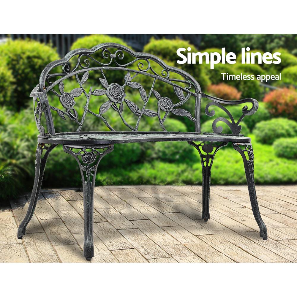 Gardeon Victorian Garden Bench in green with ornate aluminum seat and floral-patterned backrest, set against a garden backdrop.