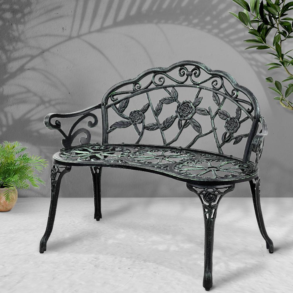 Gardeon Victorian Garden Bench in green with ornate aluminum seat and floral-patterned backrest, set against a garden backdrop.