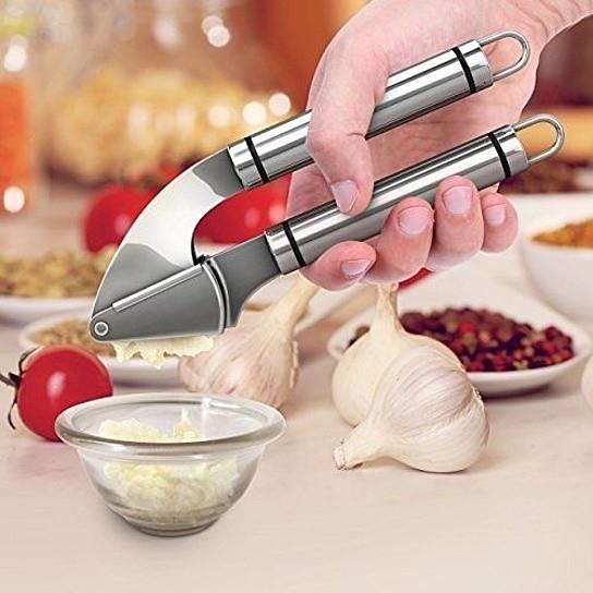 Stainless steel Garlic Press PRO with silicone peeler and cleaning brush, designed for easy garlic mincing.