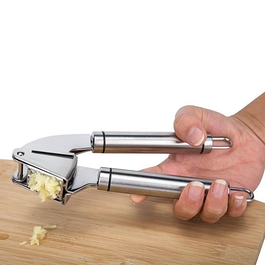 Stainless steel Garlic Press PRO with silicone peeler and cleaning brush, designed for easy garlic mincing.