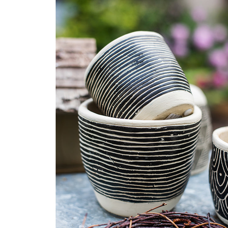 Geometric Art Concrete Flower Pot in black and cream colors, showcasing its modern design and drainage hole.