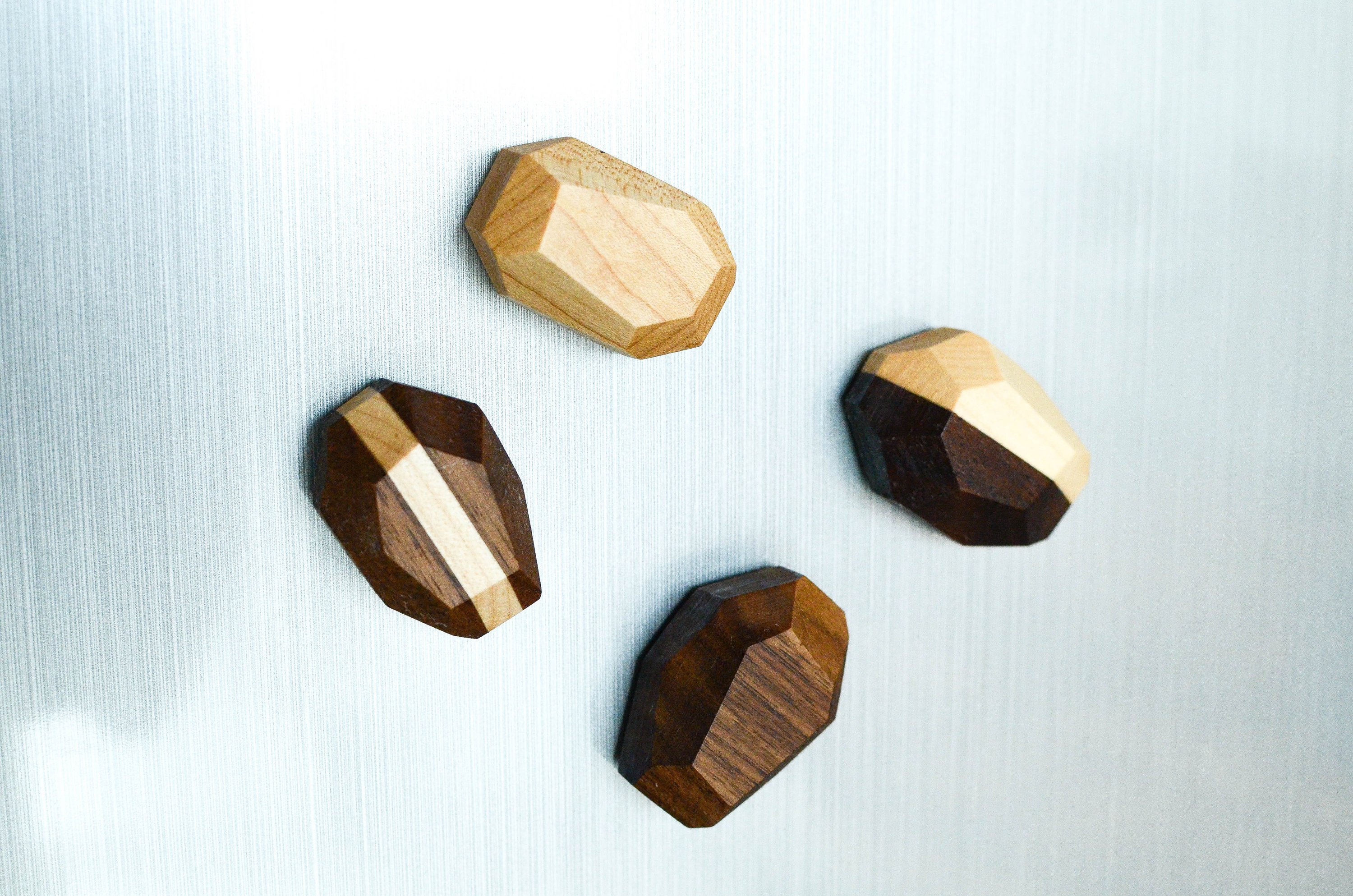 Set of 4 unique geometric wooden magnets in various shapes, crafted from Black Walnut and Maple, showcasing a natural finish.