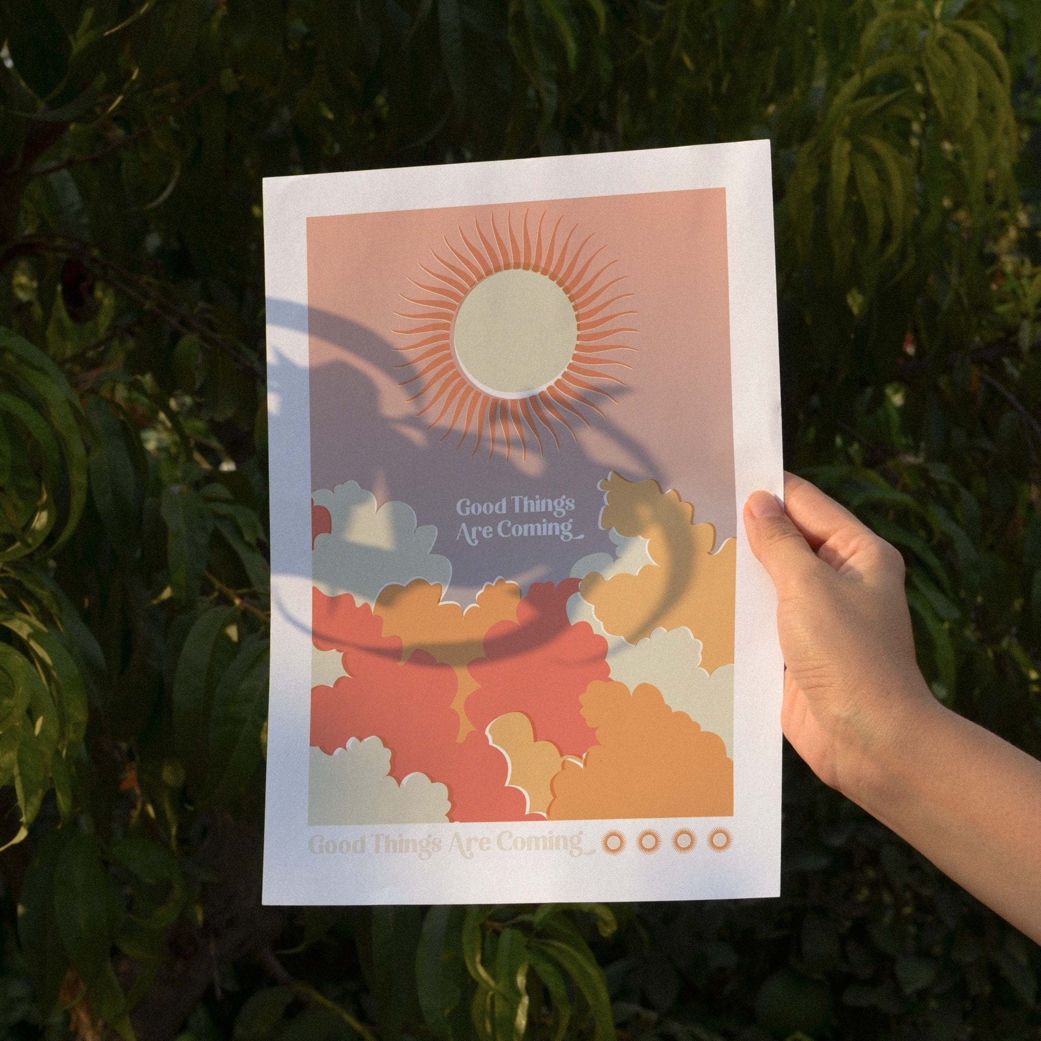 Good Things Are Coming art print featuring retro word art with sun and cloud imagery in warm colors.