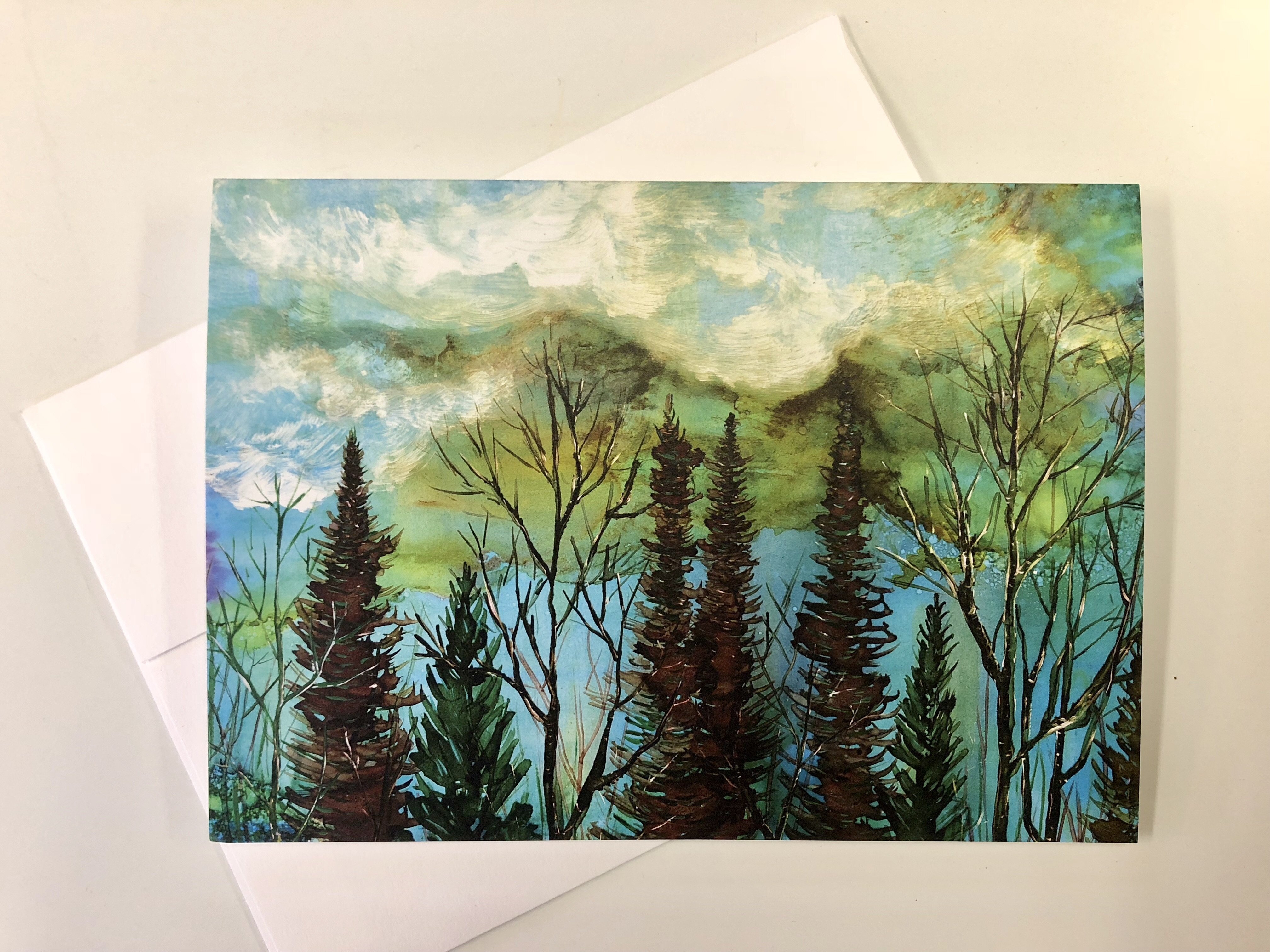 A beautiful greeting card featuring a moody landscape with a vibrant green sky and a tranquil forest below, perfect for gifting or framing.