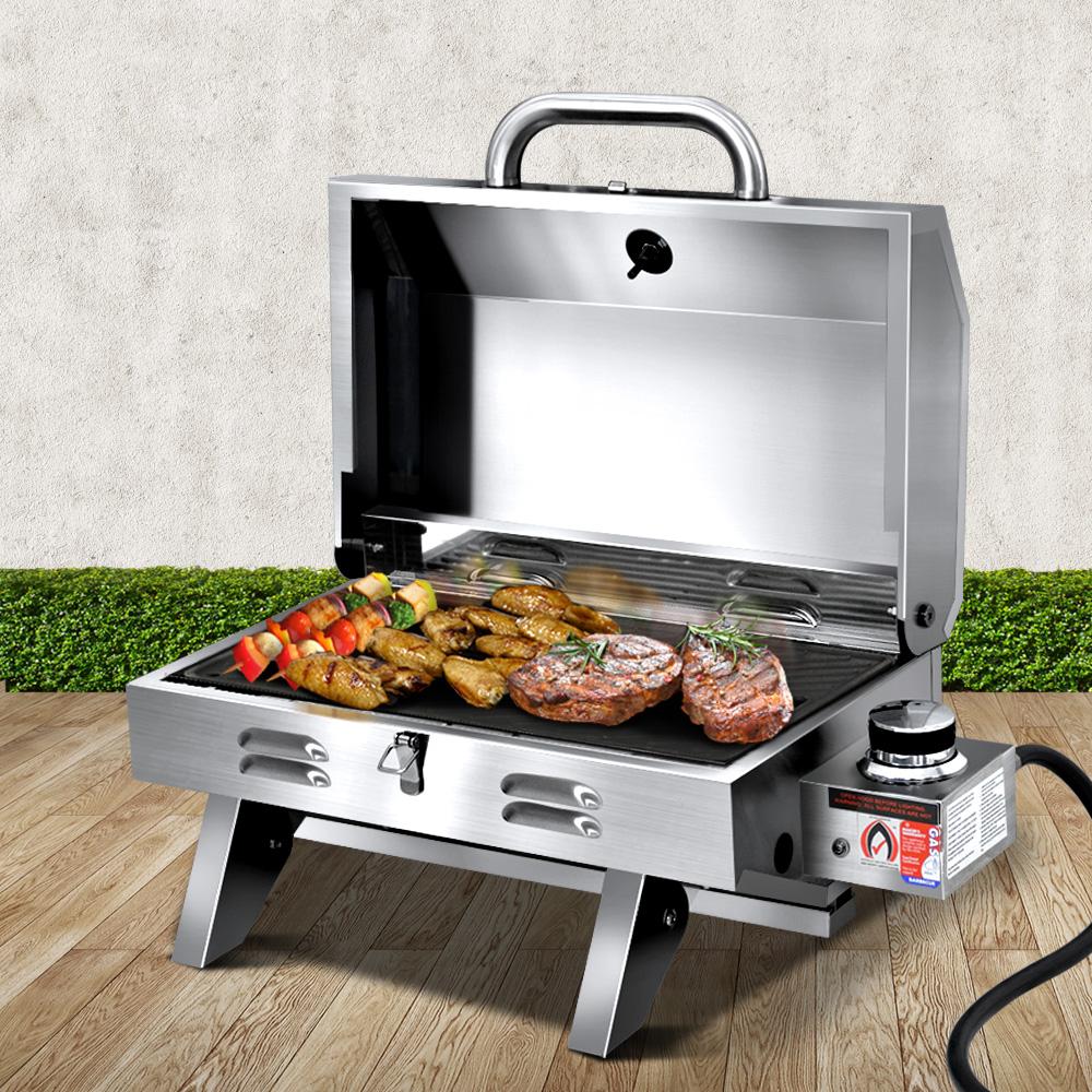 Grillz Portable Gas BBQ with foldable legs and stainless steel finish, showcasing its double-sided grill plate and integrated thermometer.