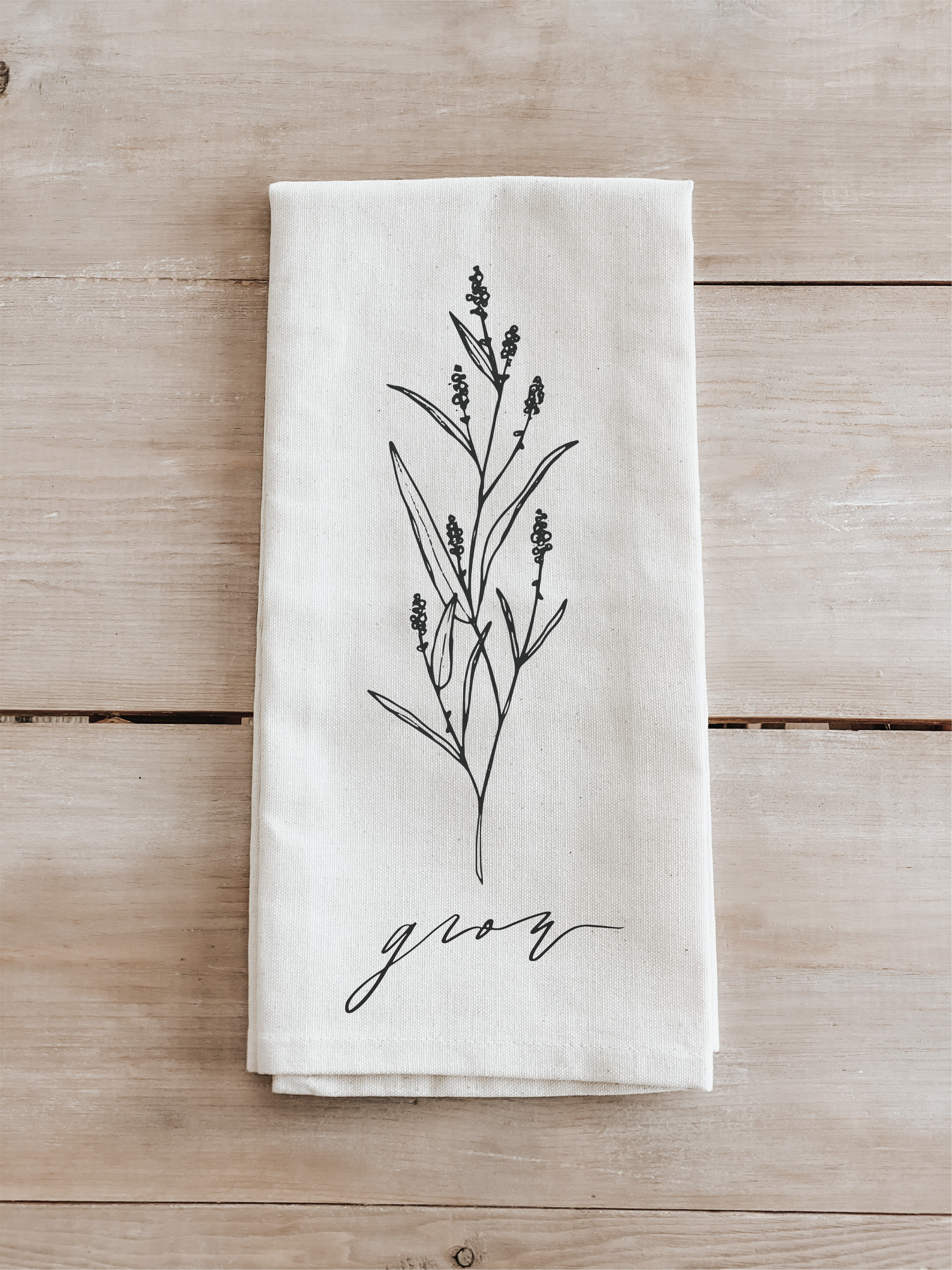 A beautifully designed Grow Wildflower Kitchen Towel made from 100% organic cotton, featuring a charming wildflower motif in white and natural colors.