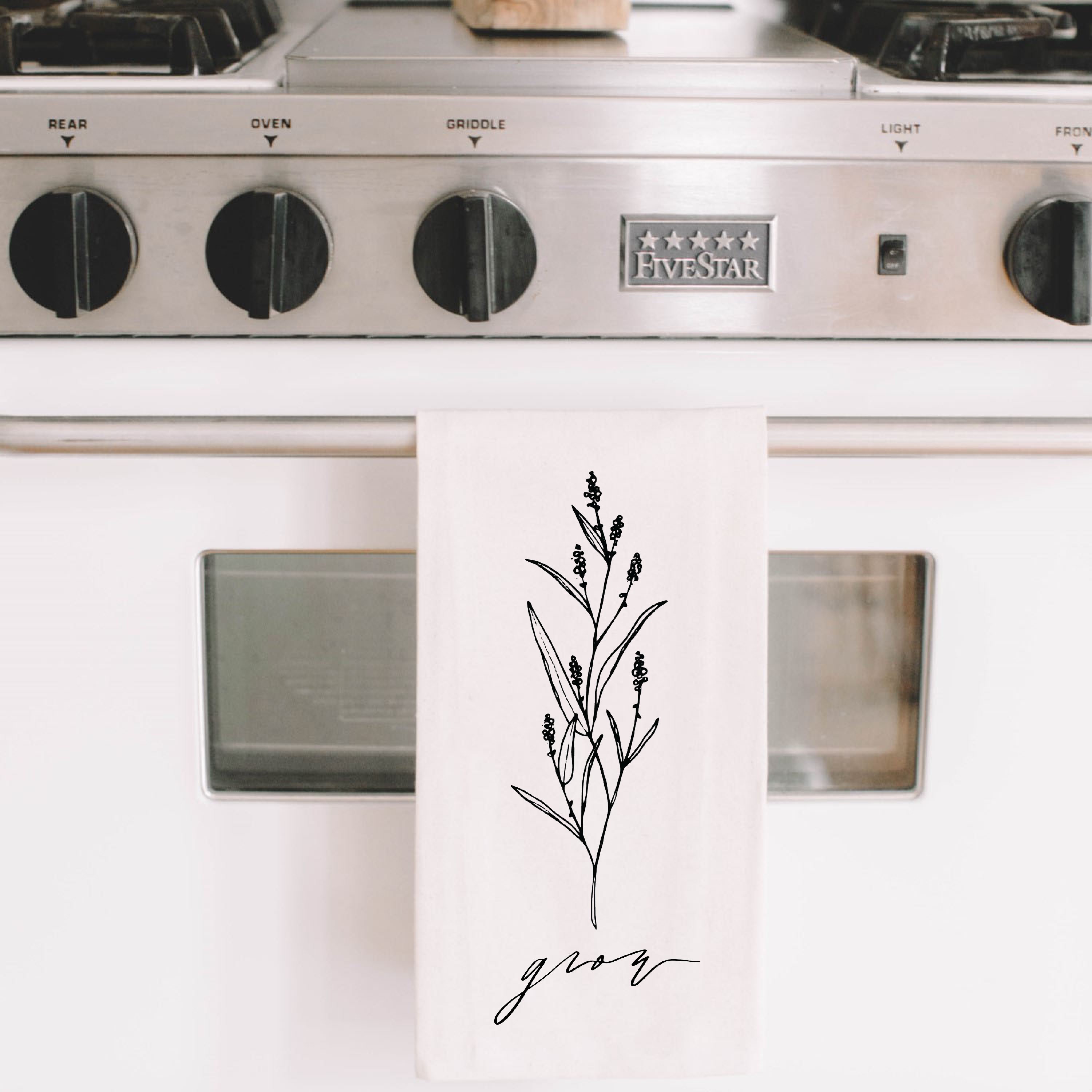 A beautifully designed Grow Wildflower Kitchen Towel made from 100% organic cotton, featuring a charming wildflower motif in white and natural colors.