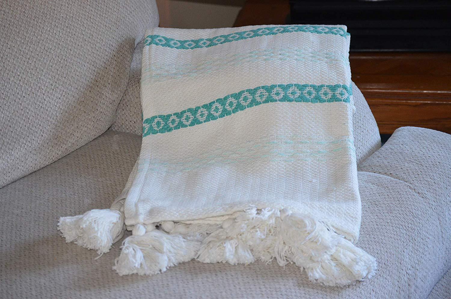 Handloom woven throw blanket in turquoise and white with chunky tassels, showcasing slub texture and elegant design.