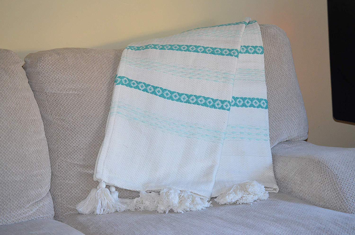 Handloom woven throw blanket in turquoise and white with chunky tassels, showcasing slub texture and elegant design.