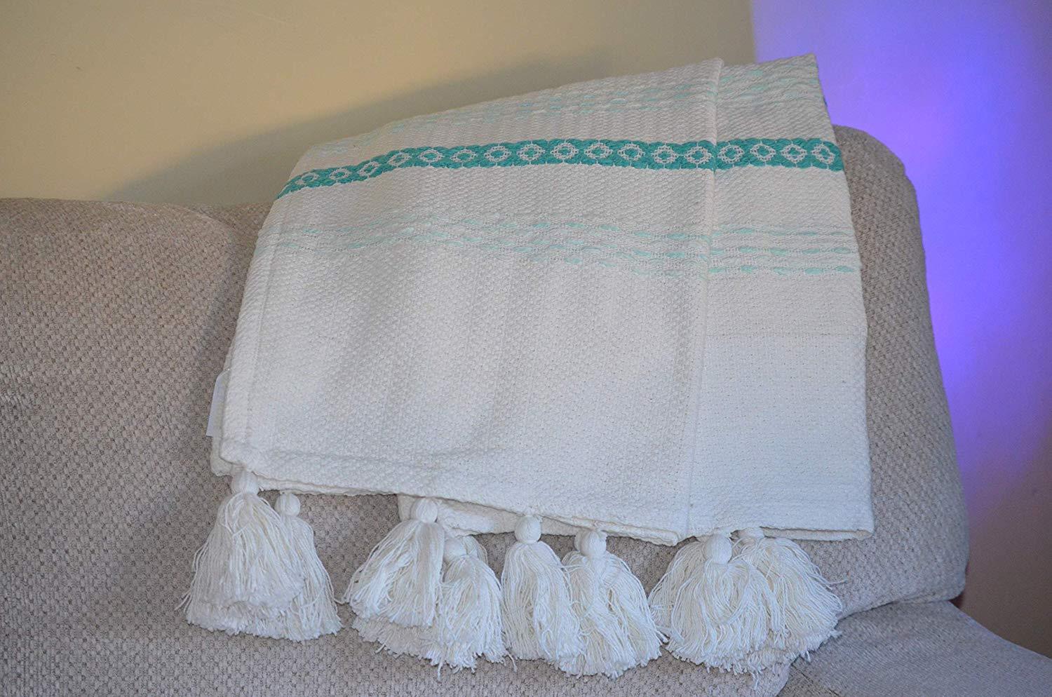 Handloom woven throw blanket in turquoise and white with chunky tassels, showcasing slub texture and elegant design.