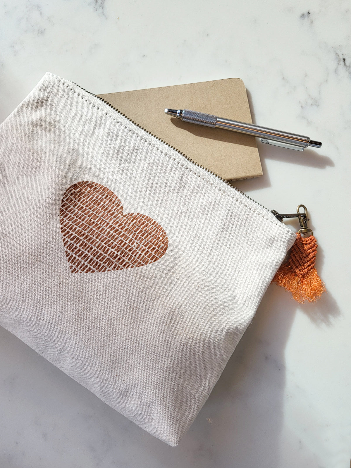 Hand screen printed cotton canvas pouch with hemp tassel, featuring a cinnamon color print on natural cream fabric.