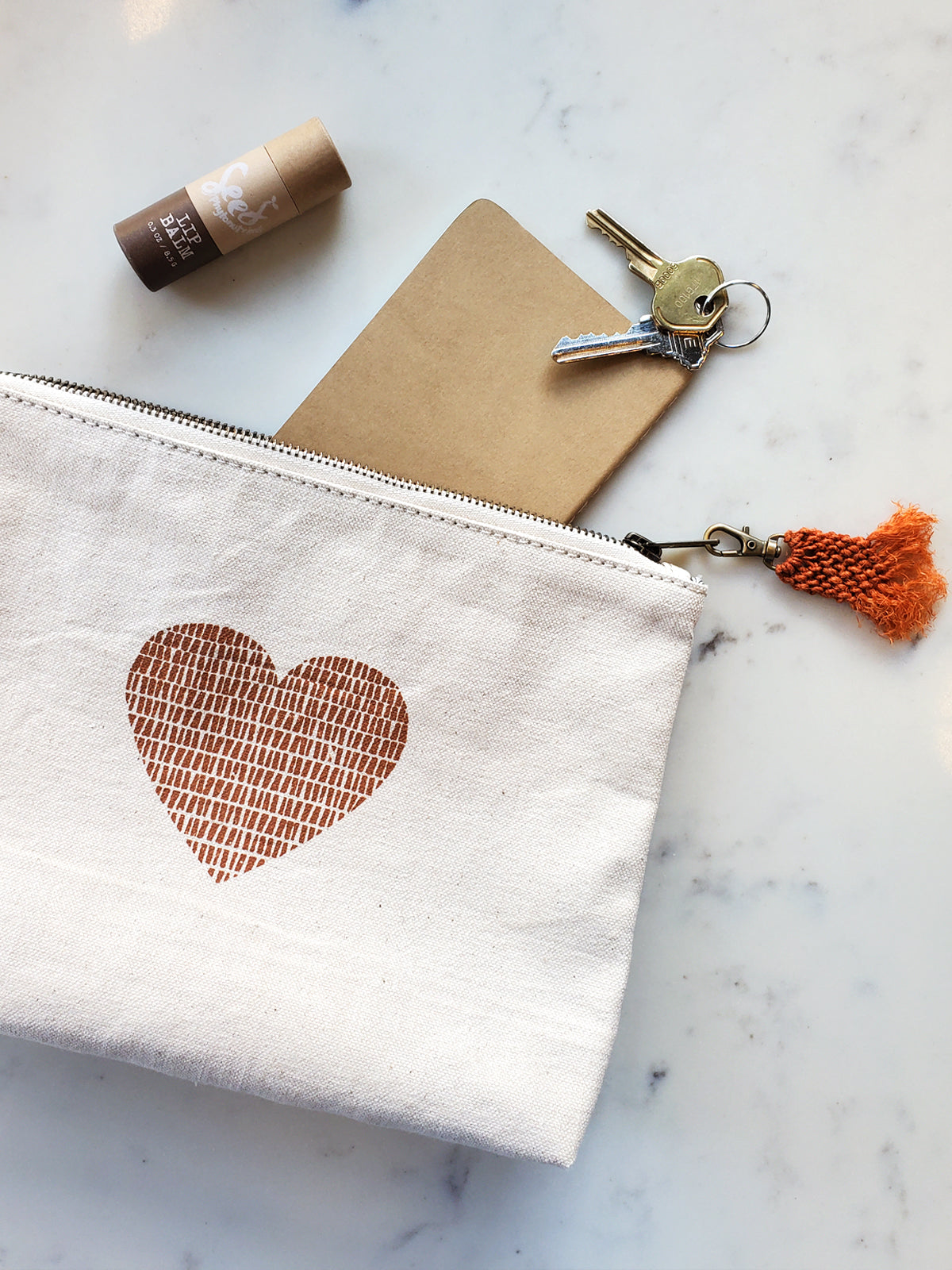 Hand screen printed cotton canvas pouch with hemp tassel, featuring a cinnamon color print on natural cream fabric.