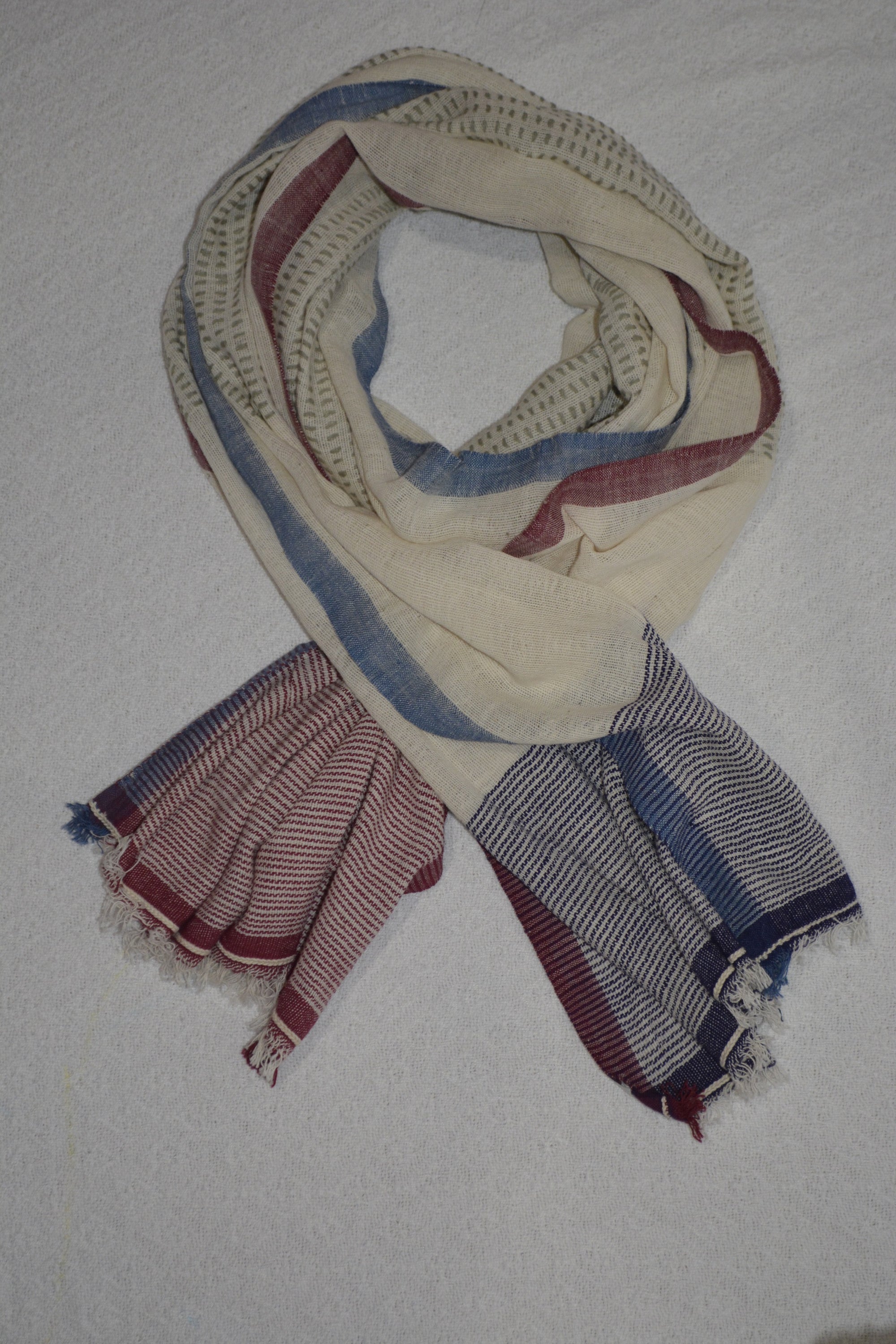 A collection of hand woven cotton scarves in various colors and patterns, showcasing the intricate craftsmanship and soft texture of Khadi cotton.