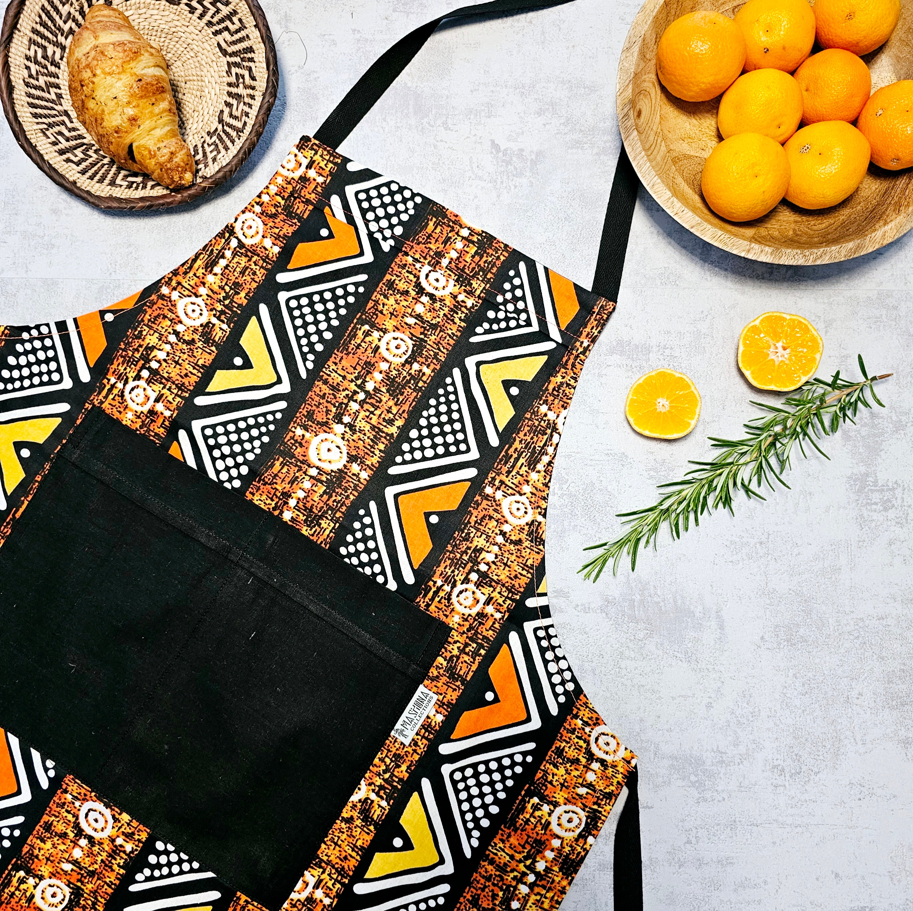 A vibrant Handmade African Print Apron featuring a traditional 'Bogolan' design, made from 100% cotton with a convenient pocket.