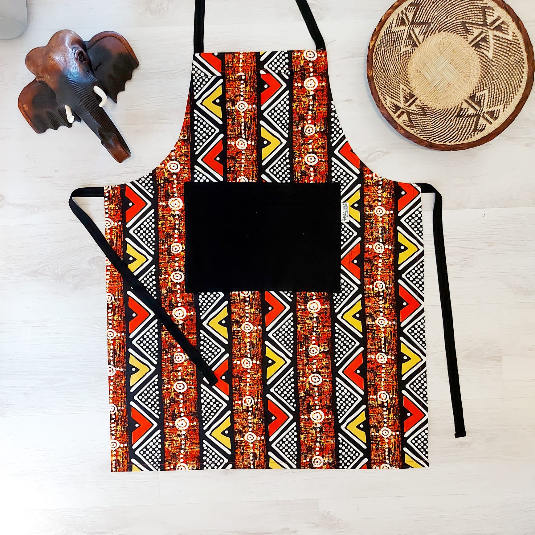 A vibrant Handmade African Print Apron featuring a traditional 'Bogolan' design, made from 100% cotton with a convenient pocket.