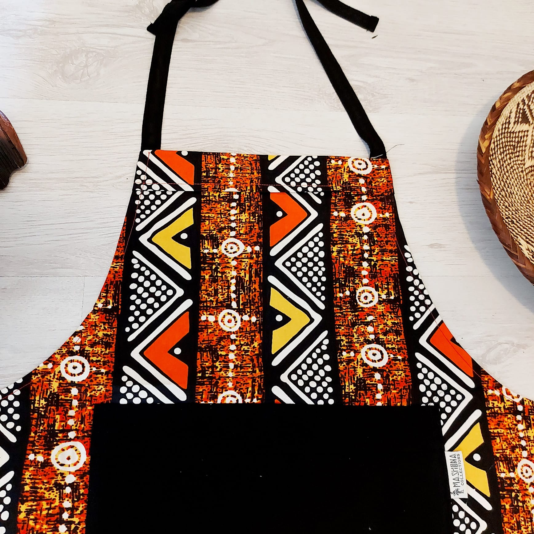 A vibrant Handmade African Print Apron featuring a traditional 'Bogolan' design, made from 100% cotton with a convenient pocket.