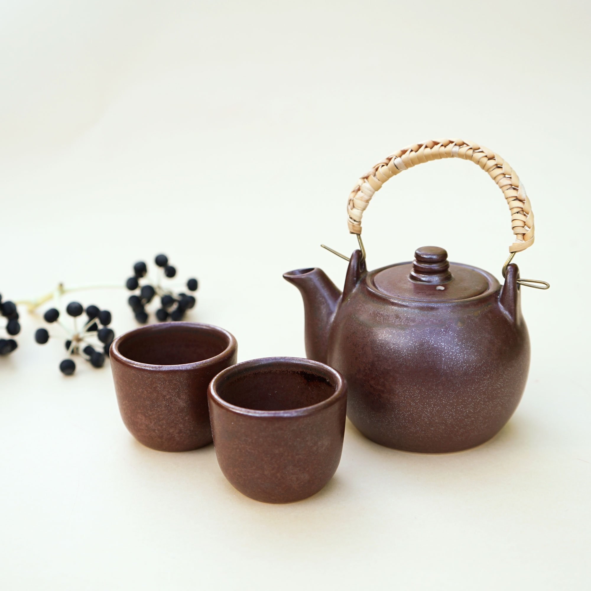 Handmade Chinese teapot set featuring a rustic design with two matching cups and a woven rattan handle.