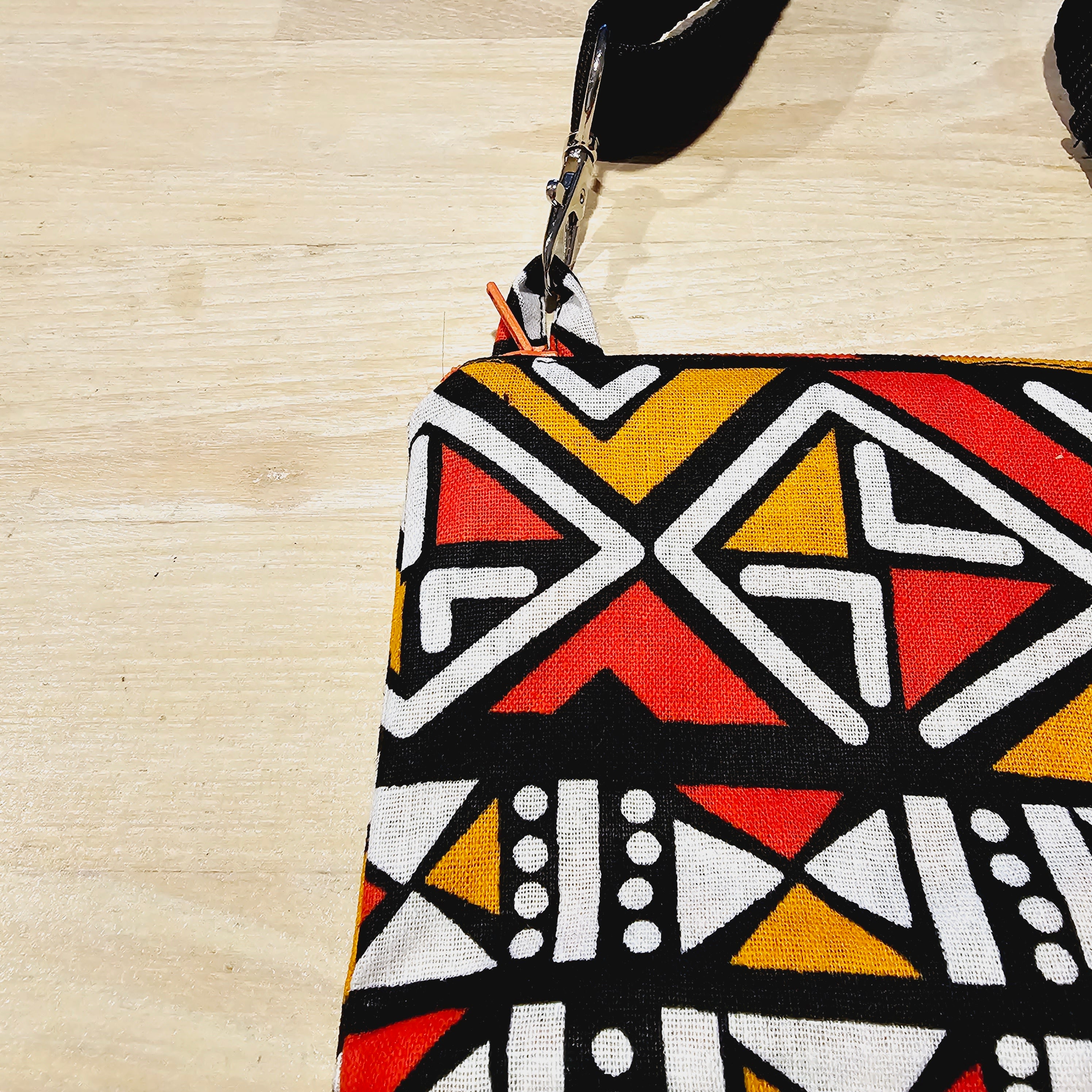 Handmade phone bag featuring vibrant African Ankara print fabric with vegan leather details and detachable wristlet key fob.