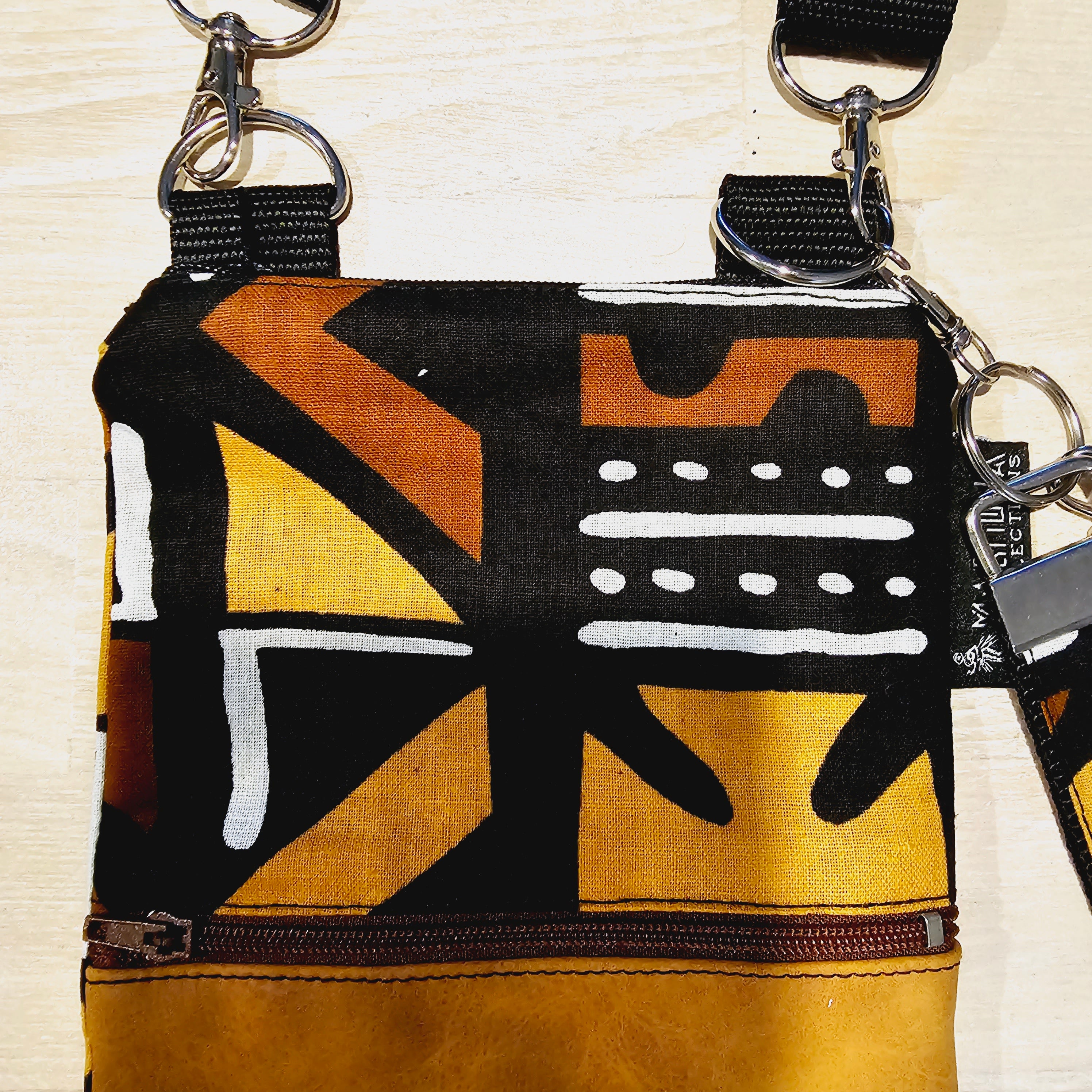 Handmade phone bag featuring vibrant African Ankara print fabric with vegan leather details and detachable wristlet key fob.